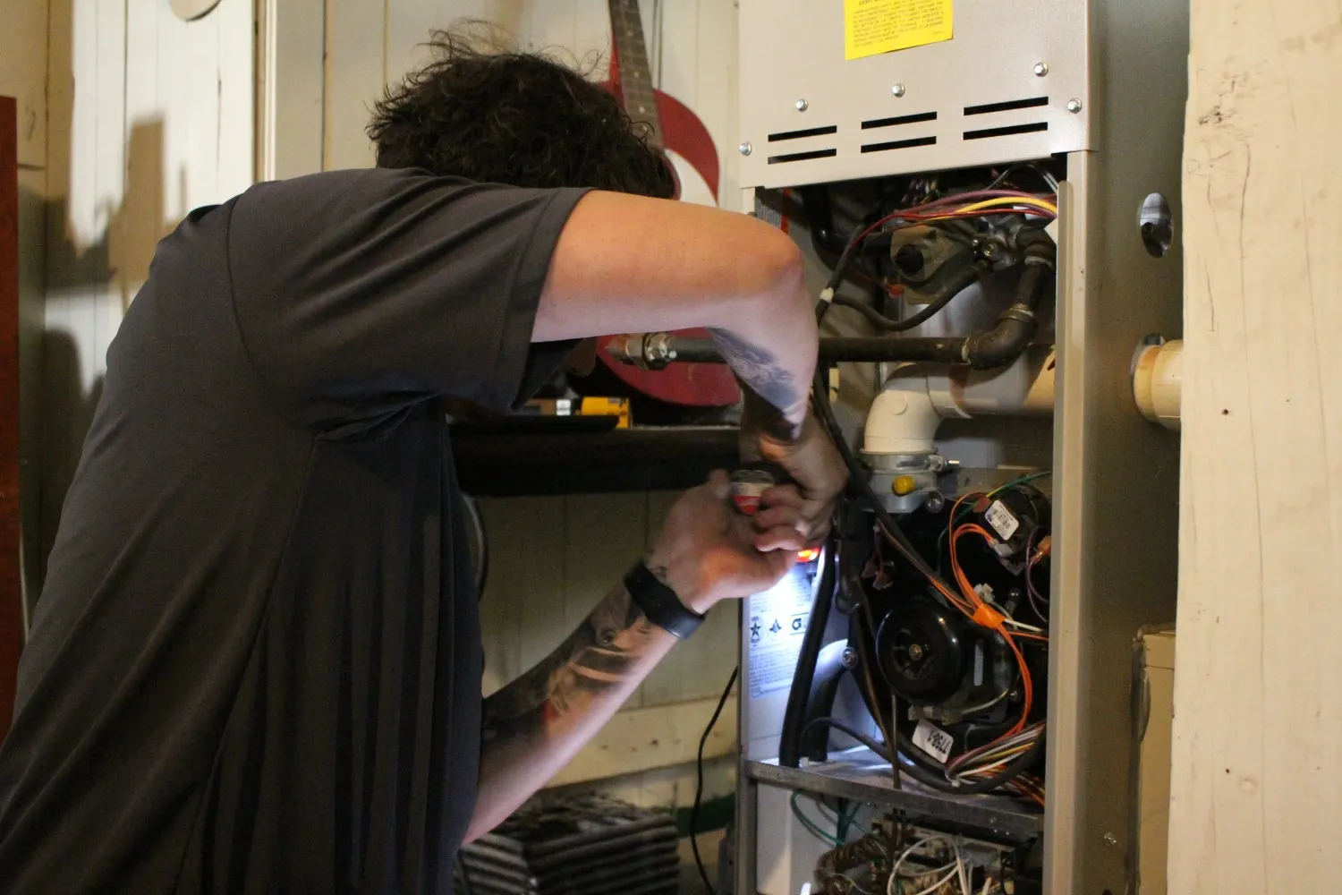 A residential furnace technician working on heating equipment