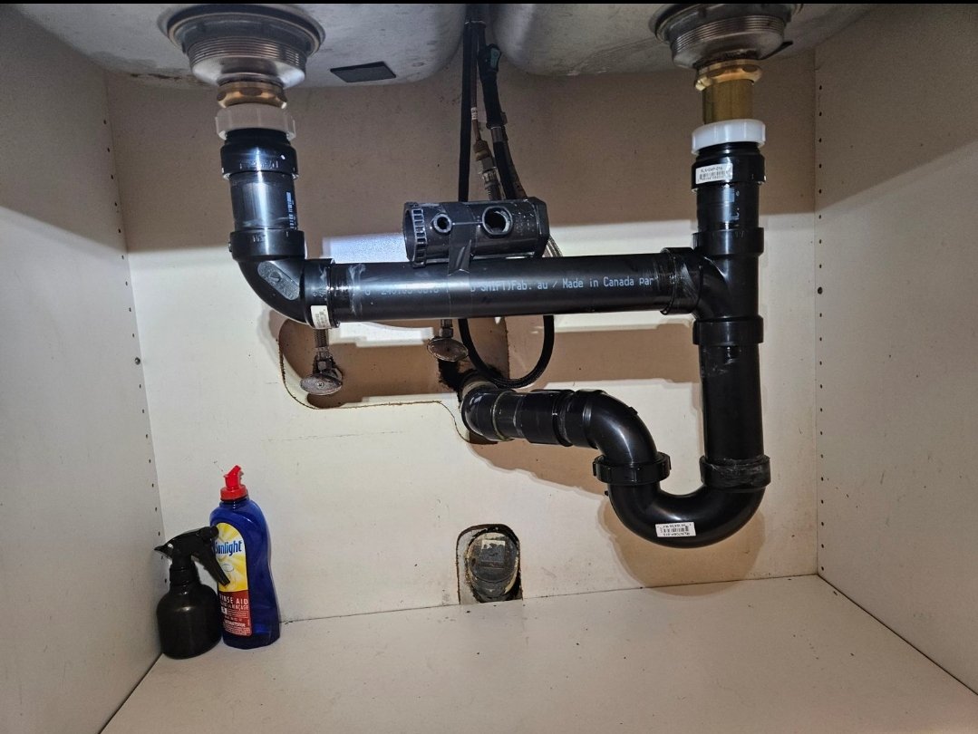 Supply lines and a drain assembly arranged beneath a kitchen sink