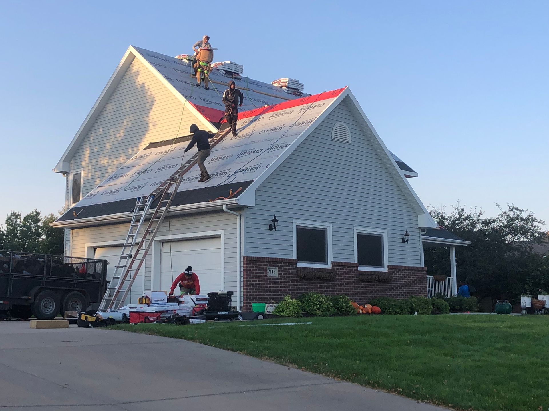 A residential roofing crew laying new roof materials across a house