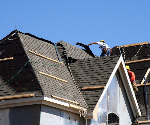 Roofers installing shingles as part of a complete residential roof replacement