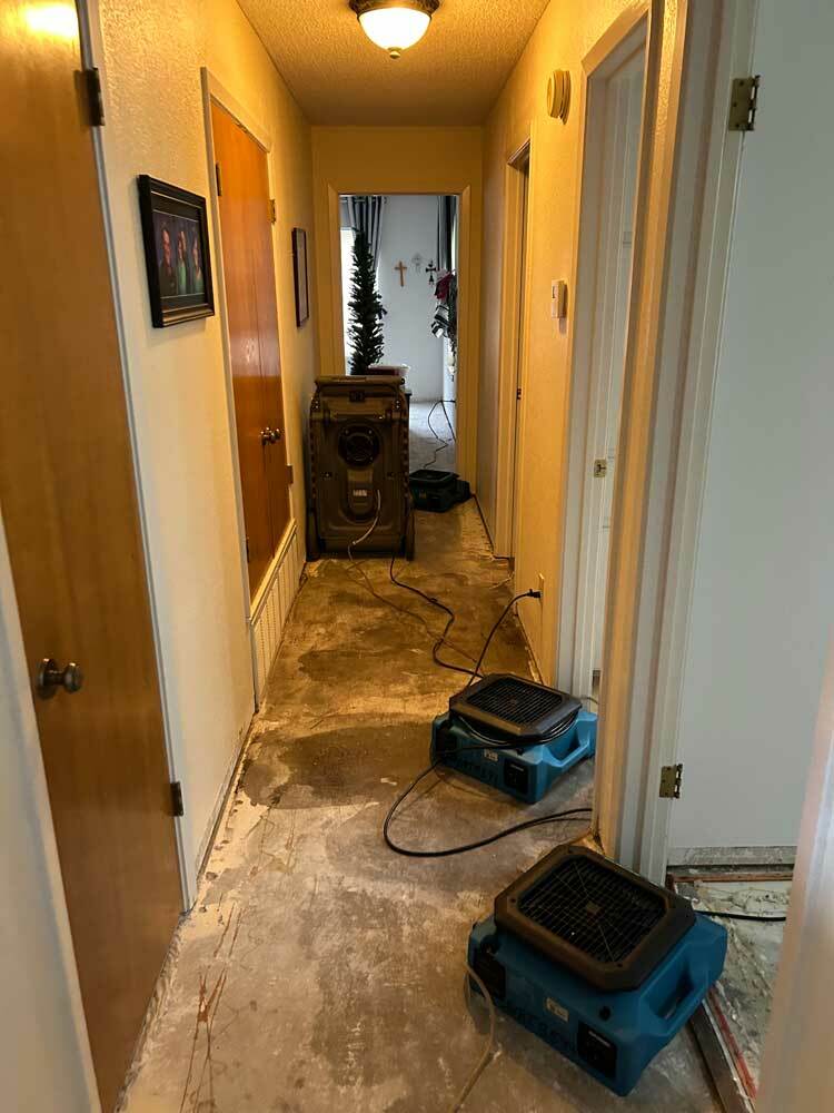 Indoor hallway with air movers and a dehumidifier arranged for structural drying